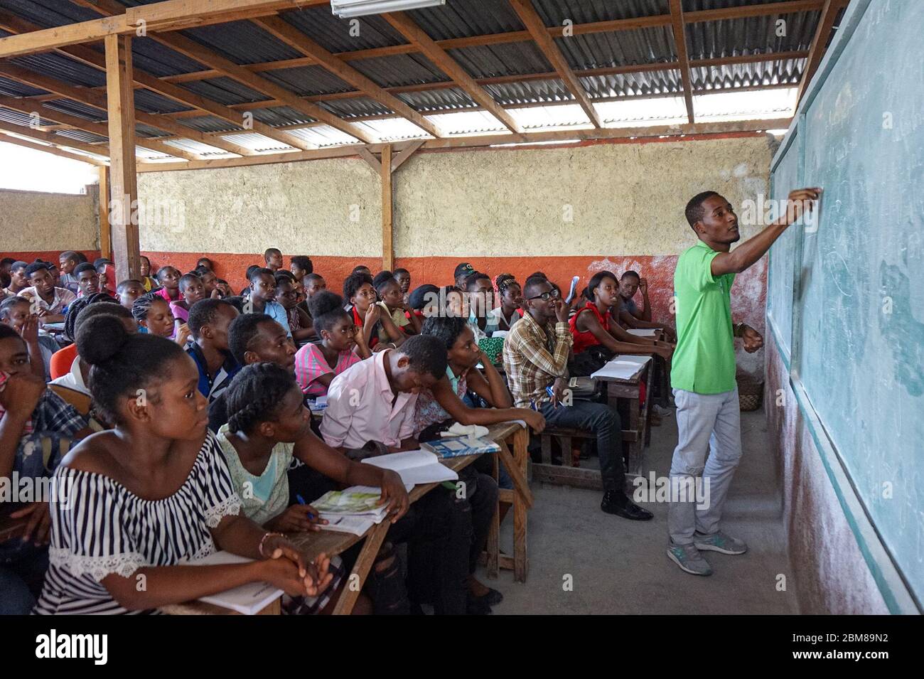Instructor Schneider Jacinthe from the CHAPEAU volunteer organization guides students through the general knowledge section of the State University of Haiti’s admissions test in a classroom in the neighborhood of Carrefour, Port-au-Prince. (Anne Myriam Bolivar, GPJ Haiti) Stock Photo