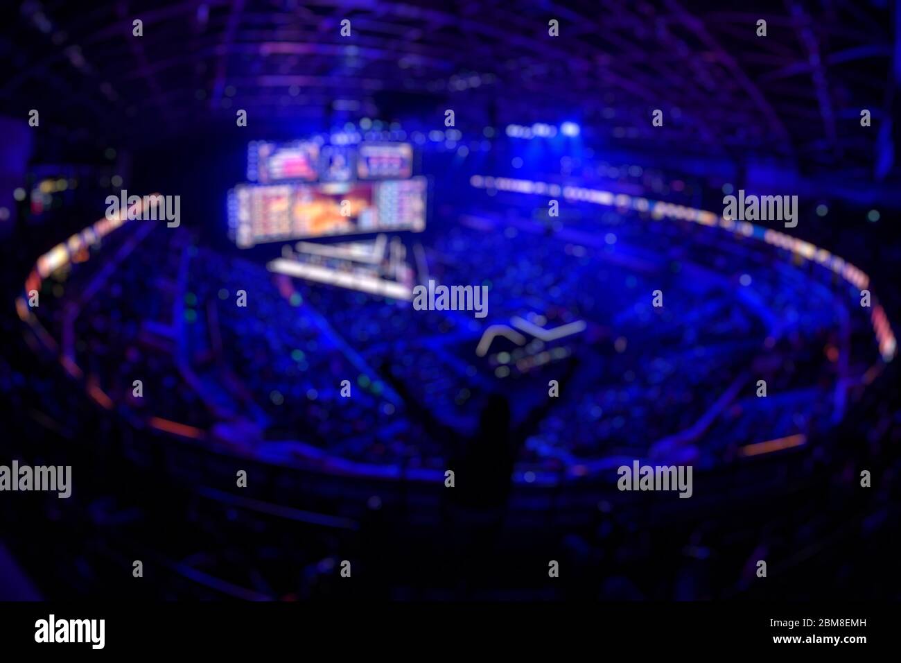 Blurred background of an esports event - Fan on a tribune at tournament's arena with hands raised. Stock Photo