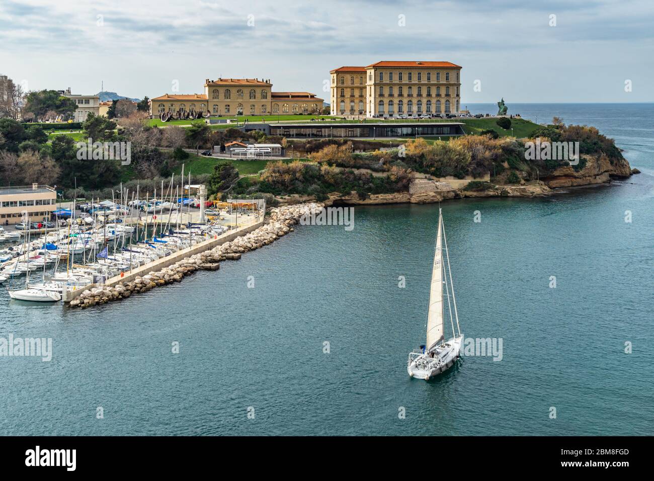 A sailboat leaving the Marseille Old Port under the Palais du Pharo, France Stock Photo