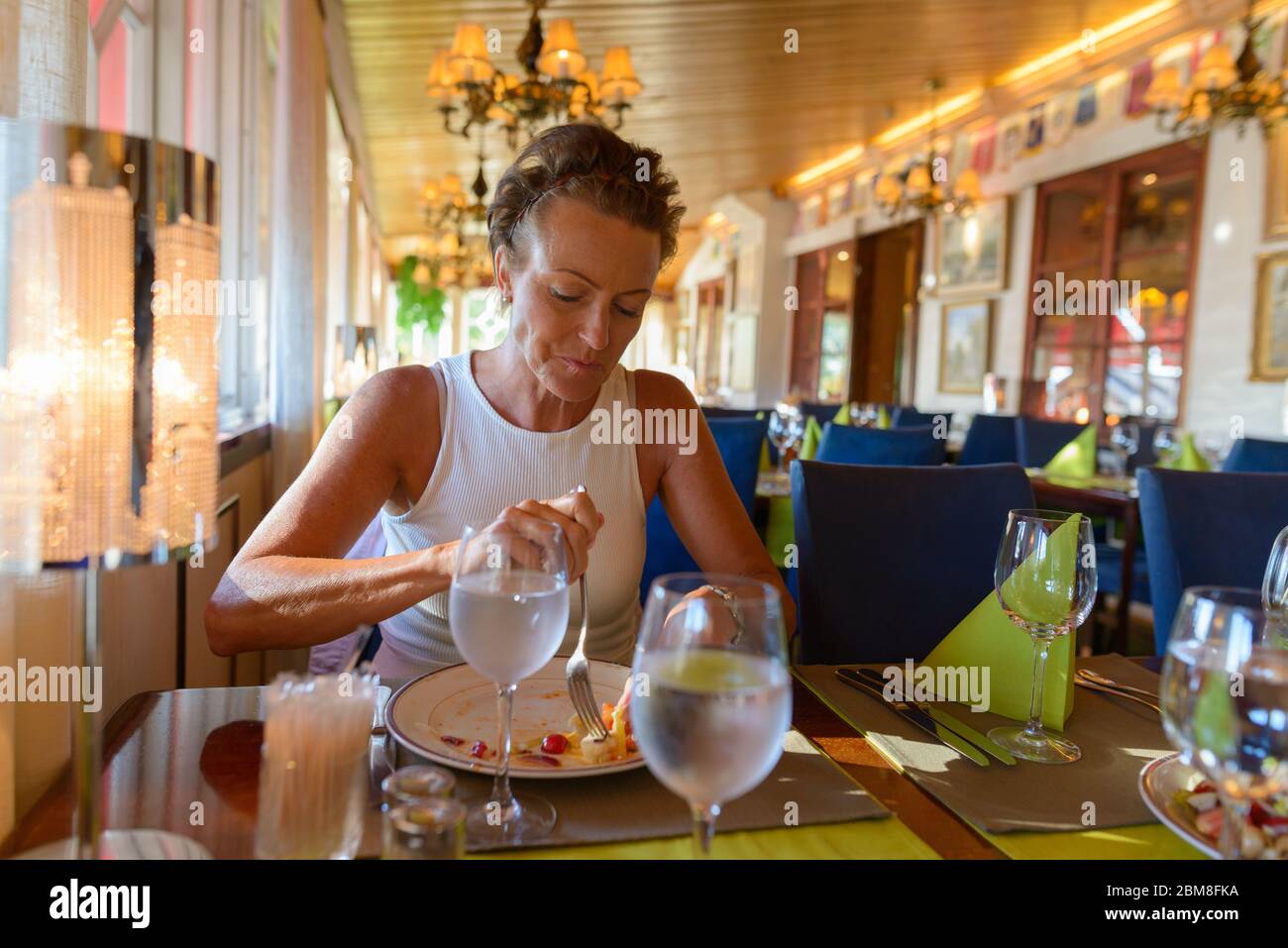 Mature beautiful woman with short hair eating at the restaurant Stock Photo