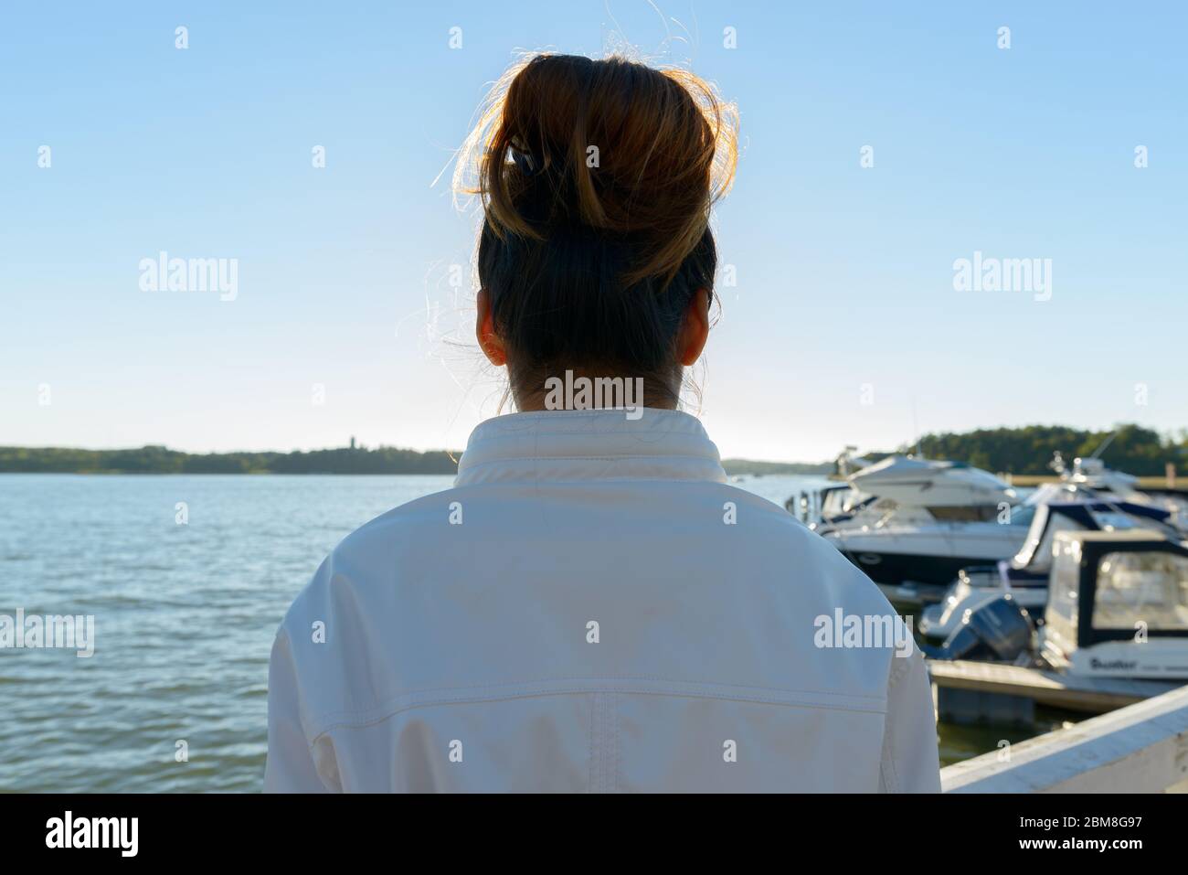 Closeup rear view of young Asian woman against beautiful scenery at the pier Stock Photo