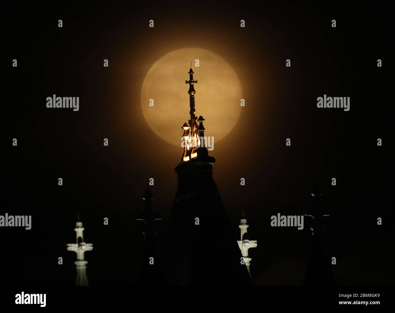 The moon rises over Tower Bridge in London, which is lit up in blue in ...