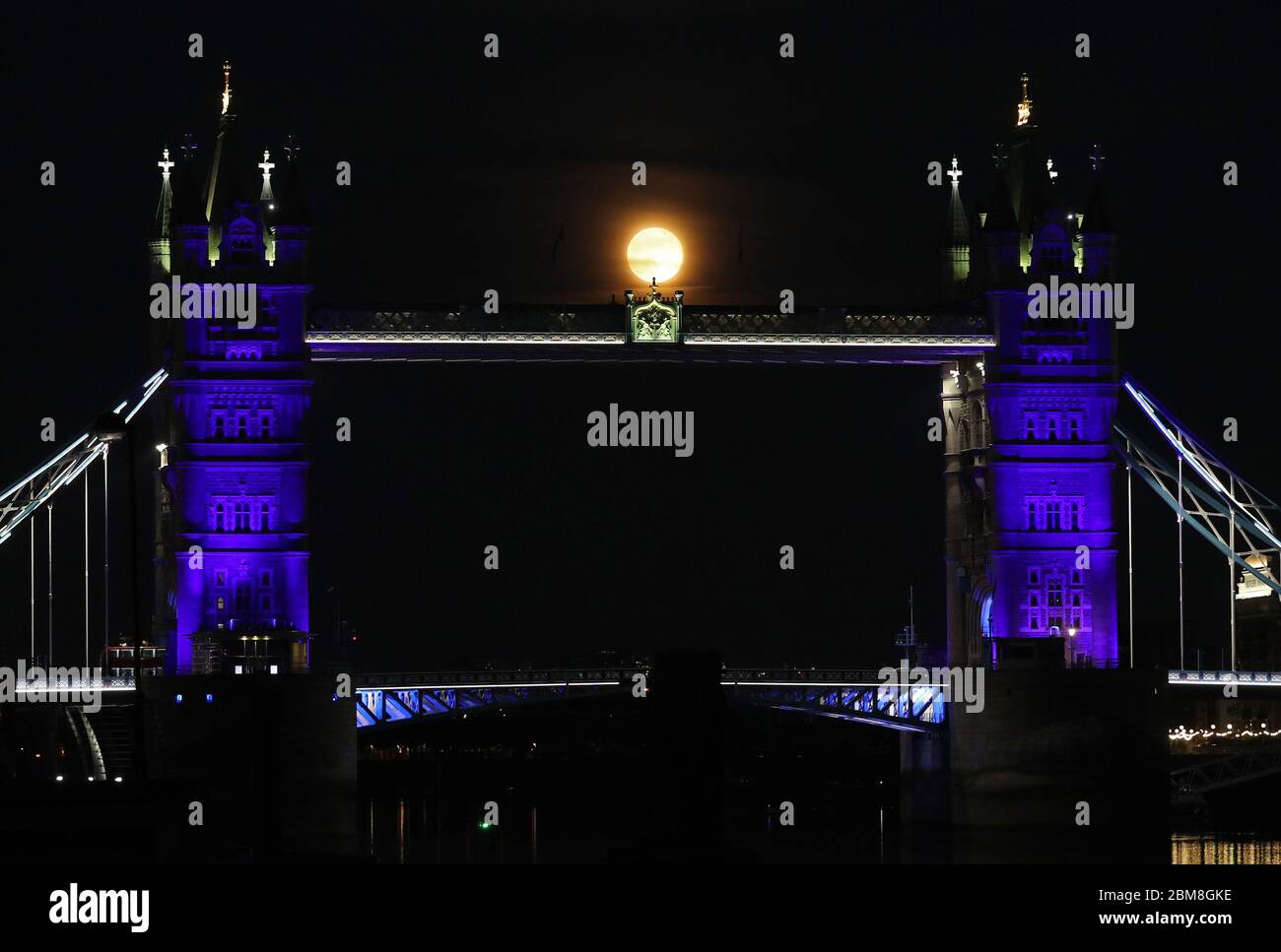 The moon rises over Tower Bridge in London, which is lit up in blue in ...