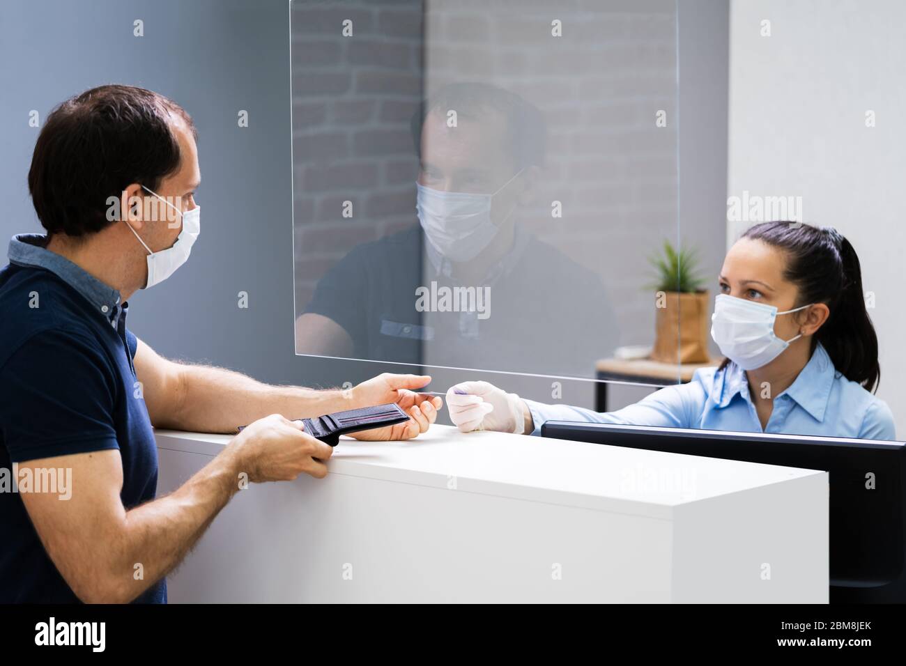 Client Handing Over Credit Card To A Cashier In Face Mask Stock Photo