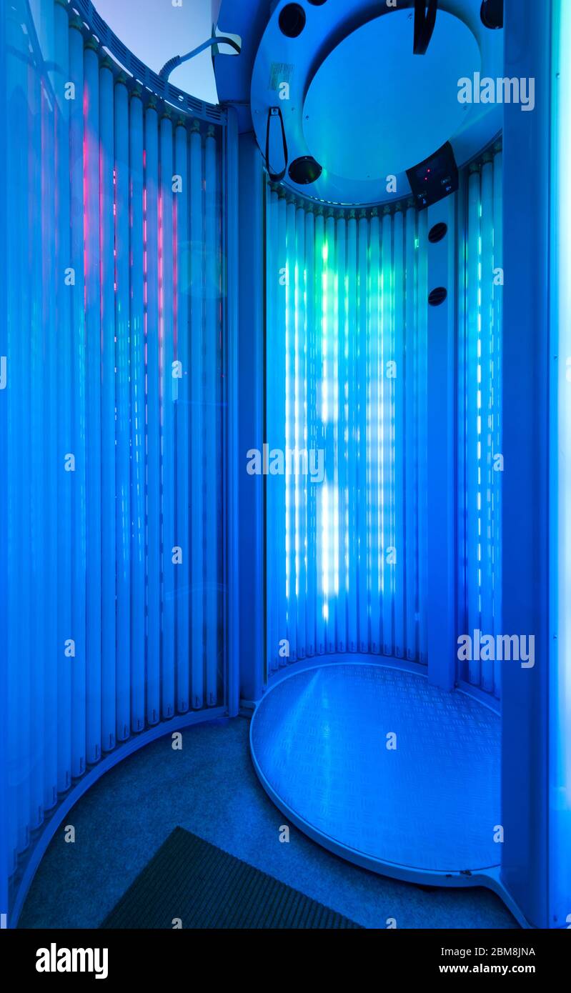 vertical Solarium with glowing blue light ultraviolet lamps for tanning and skin care Stock Photo