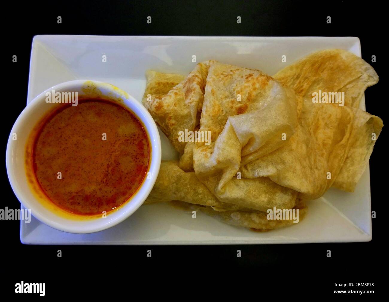 Malaysian pancake, also known as roti canai, with a side of curry gravy Stock Photo