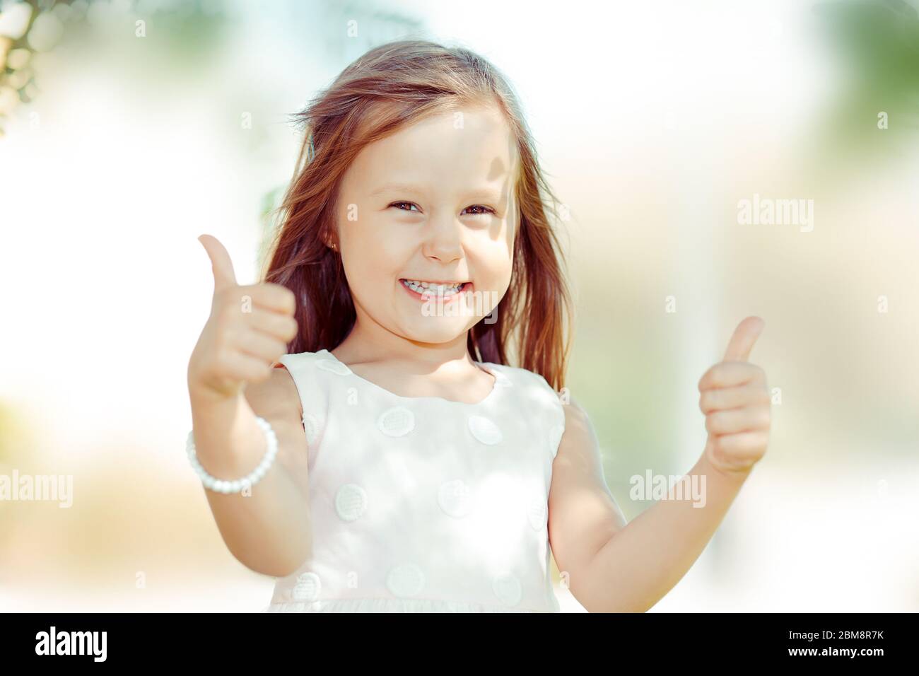 The little girl happy toddler kid showing thumbs up gesture with hands ...