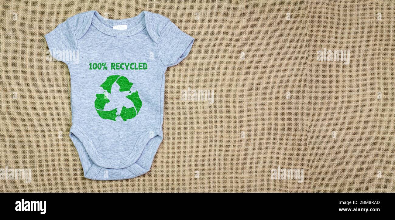 Recycled fabric baby grow with the future is green text on recycled fabric background. Copy space. Zero waste and sustainable fashion concept Stock Photo
