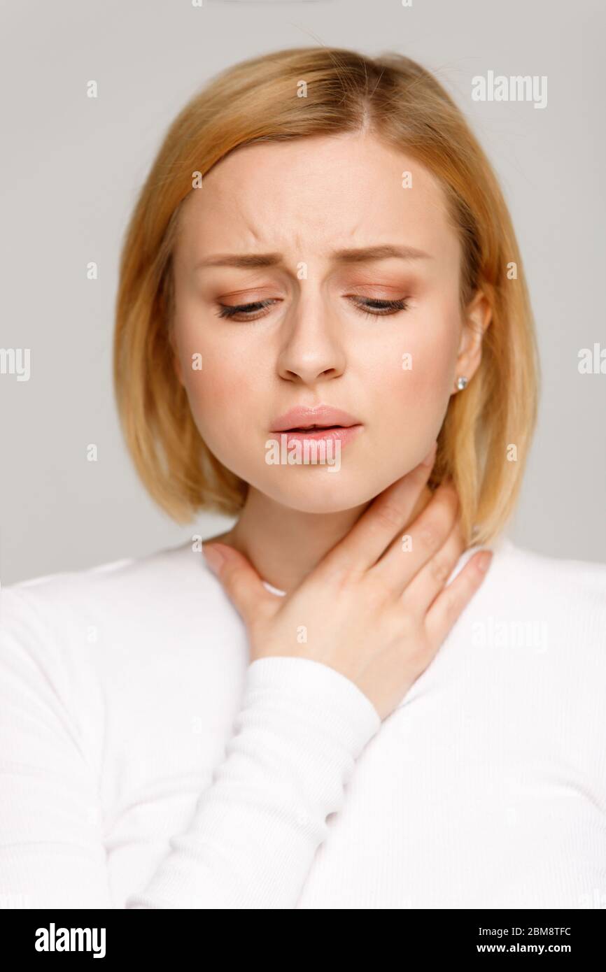 Closeup studio portrait of sick young woman suffering from throat problems. Thyroid gland, painful swallowing, tonsillitis concept. Inflammation of th Stock Photo