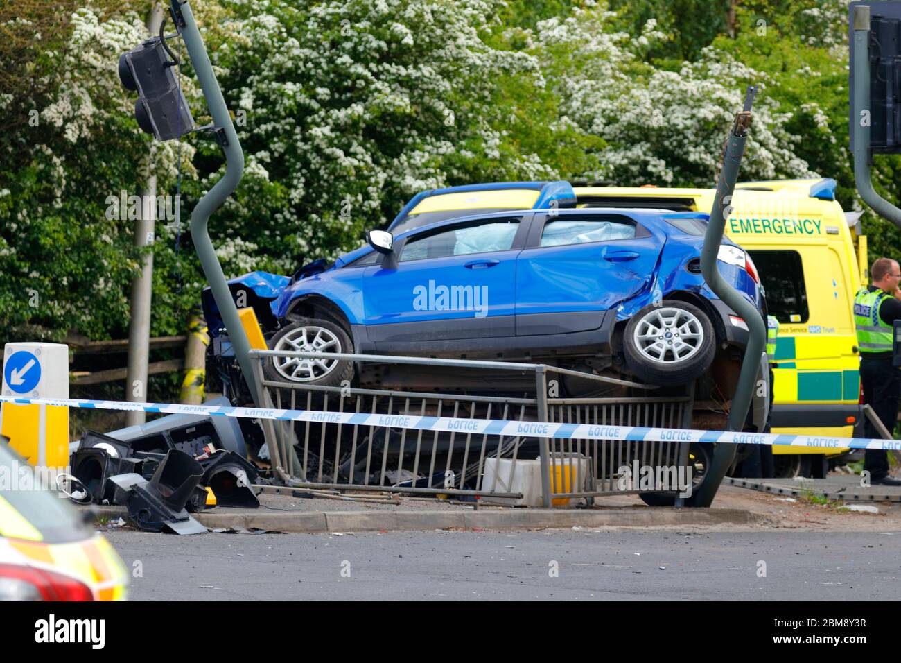 A car is left on it's side, after colliding with traffic lights at a