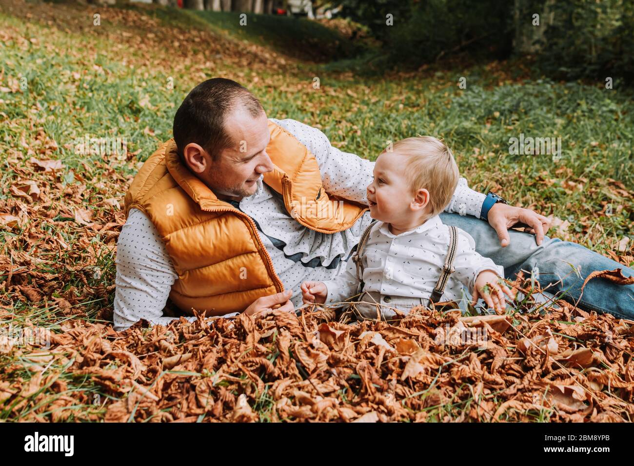 Father and 1 year old child in the park in leafs in the park Stock Photo