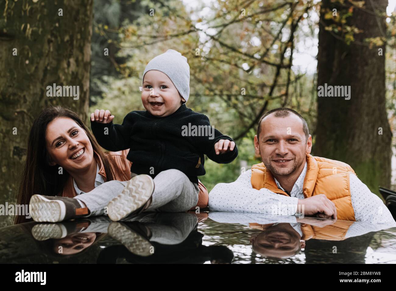 Happy family woman and man with 1 year old boy outdoors in park Stock Photo