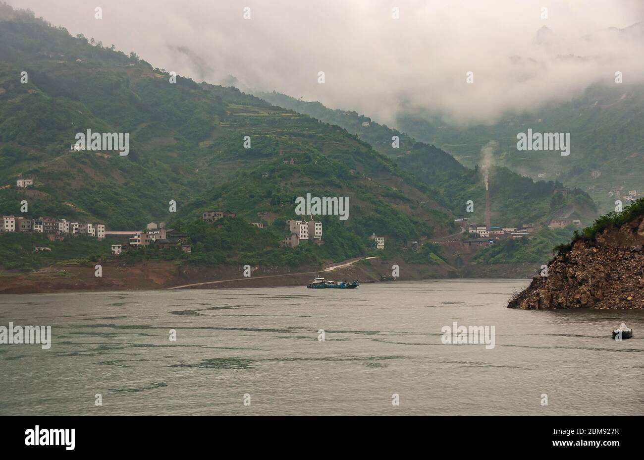 Xiangxicun, China - May 6, 2010: Xiling gorge on Yangtze River. Xiangxi river empties in Yangtze. with green mountains and gray descending cloudscape Stock Photo