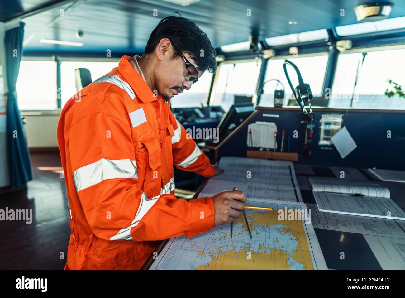 Filipino deck Officer on bridge of vessel or ship. He is plotting