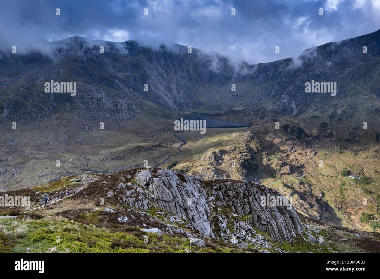 Walkers climbing Pen yr Ole Wen backed by Cwm Idwal and Glyder Fawr, Snowdonia National Park, North Wales, UK Stock Photo