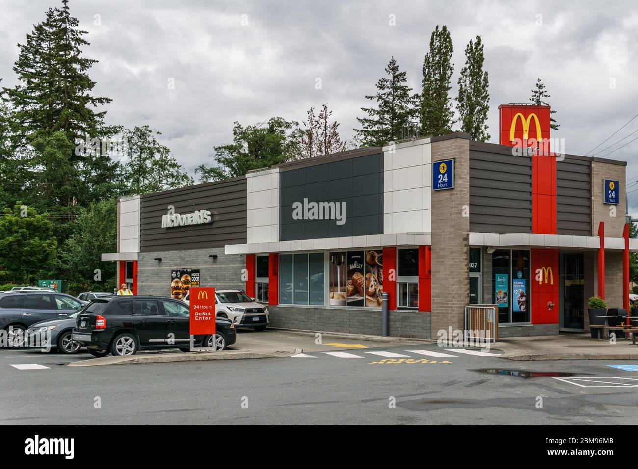 LANGLEY, CANADA - JULY 10, 2019: McDonald's restaurant building with cars on parking spot and green trees. Stock Photo