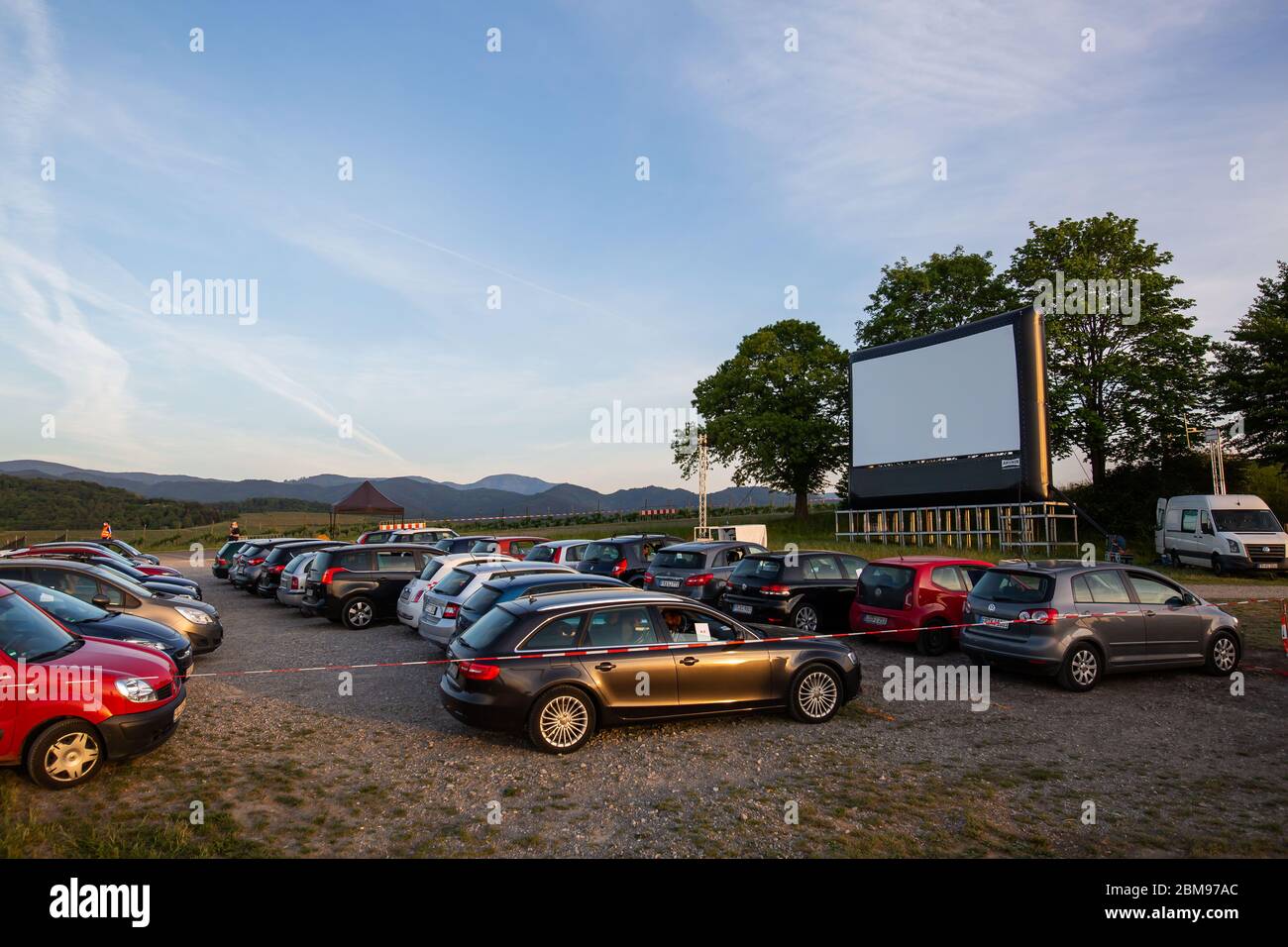 Ehrenkirchen, Germany. 07th May, 2020. Cars and an inflatable screen stand in the run-up to a drive-in cinema screening on the Batzenberg fairground, framed by a barrier tape. With the Corona crisis, the drive-in cinema is also experiencing a comeback in the southwest, as here on the Batzenberg between Ehrenkirchen and Pfaffenweiler. Credit: Philipp von Ditfurth/dpa/Alamy Live News Stock Photo