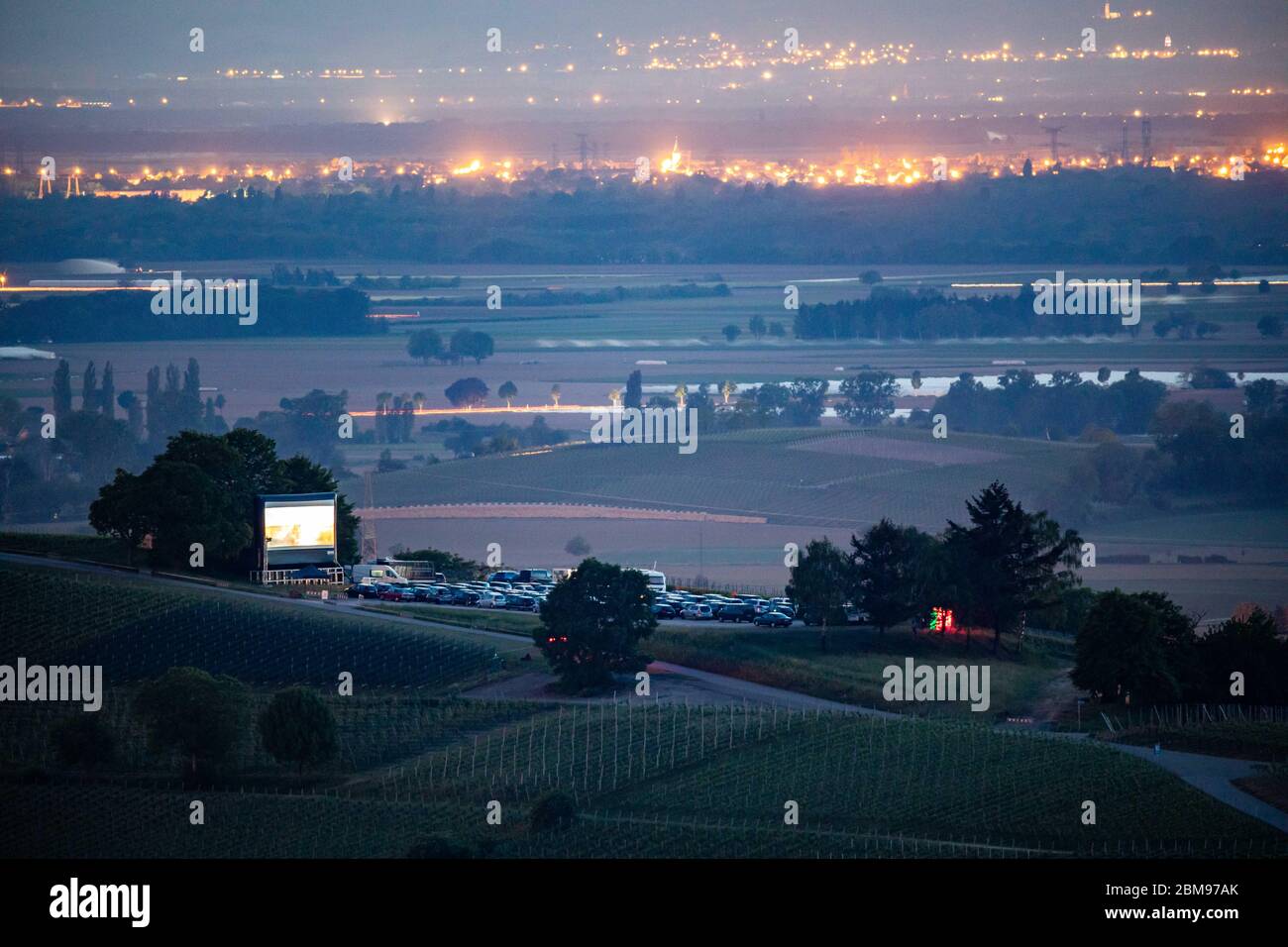 Pfaffenweiler, Germany. 07th May, 2020. Cars and an inflatable screen are parked on the Batzenberg fairground during a drive-in cinema screening, while the Rhine plains can be seen in the background. With the Corona crisis the drive-in cinema is also experiencing a comeback in the southwest, as here on the Batzenberg between Ehrenkirchen and Pfaffenweiler. Credit: Philipp von Ditfurth/dpa/Alamy Live News Stock Photo