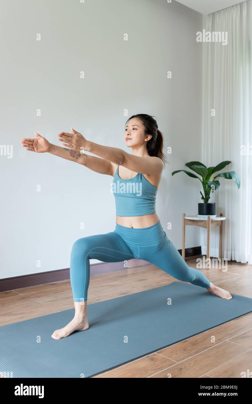 A young Asian woman doing yoga at home Stock Photo - Alamy