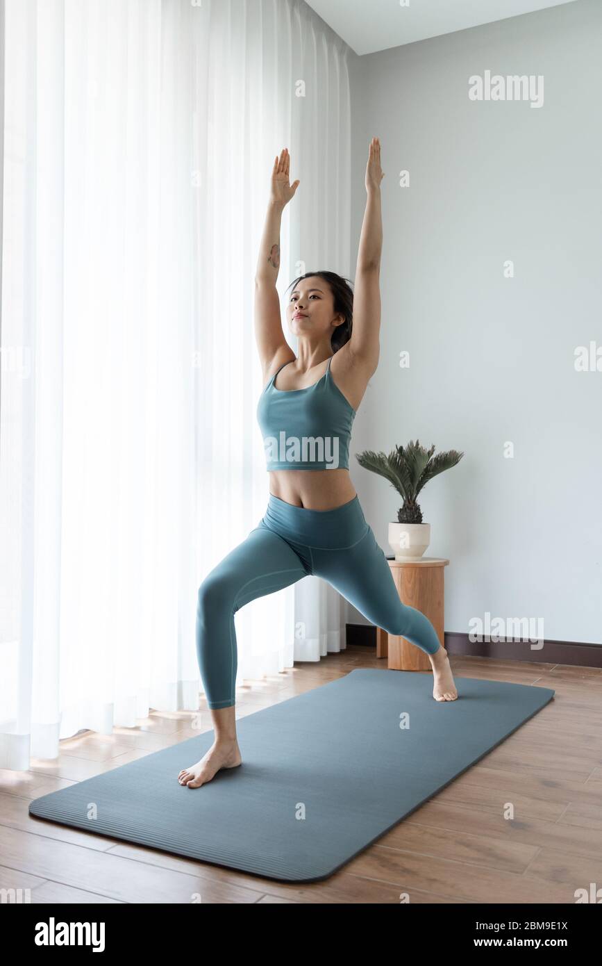 A young Asian woman doing yoga at home Stock Photo - Alamy