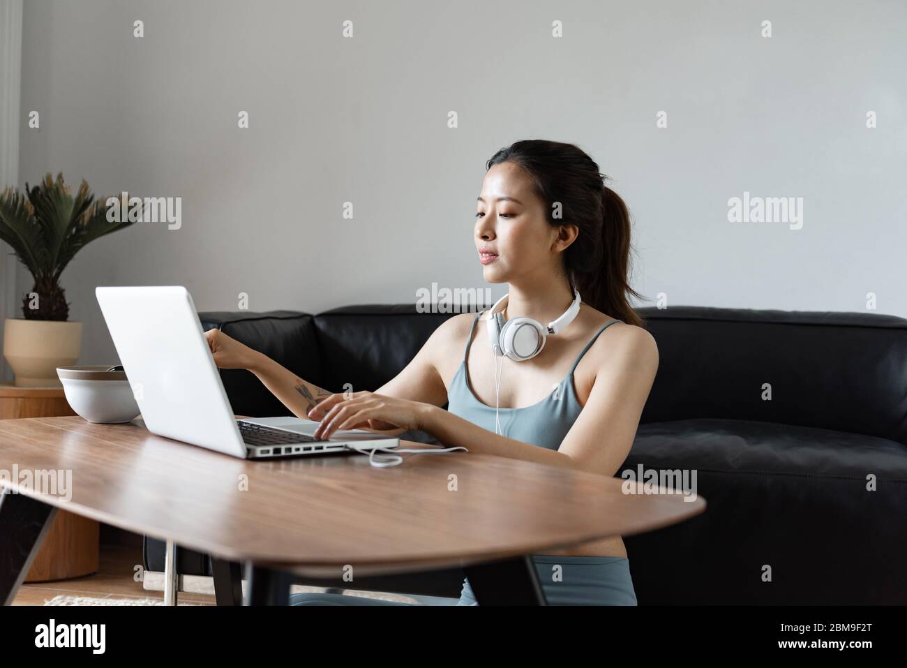 A young Asian woman using a computer in the living room Stock Photo