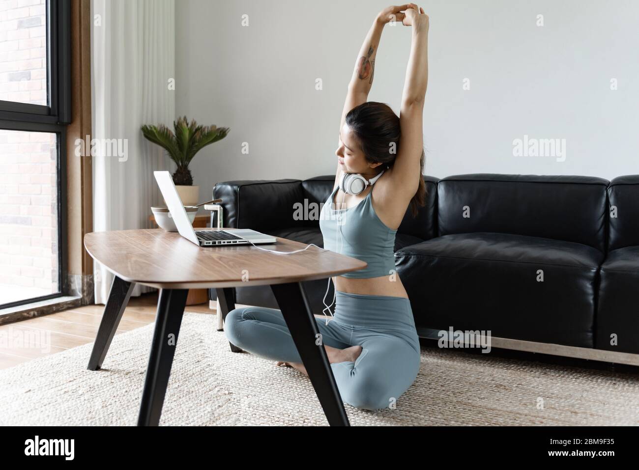 A young Asian woman using a computer in the living room Stock Photo