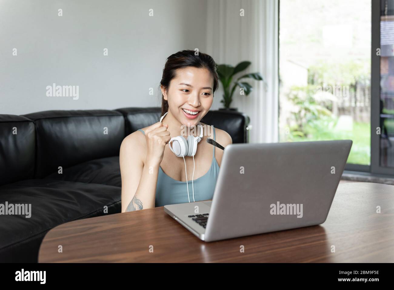 A young Asian woman using a computer in the living room Stock Photo - Alamy