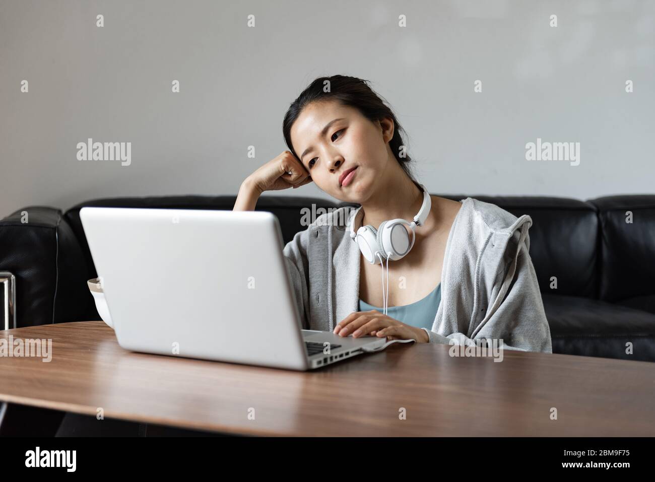 A young Asian woman using a computer in the living room Stock Photo - Alamy