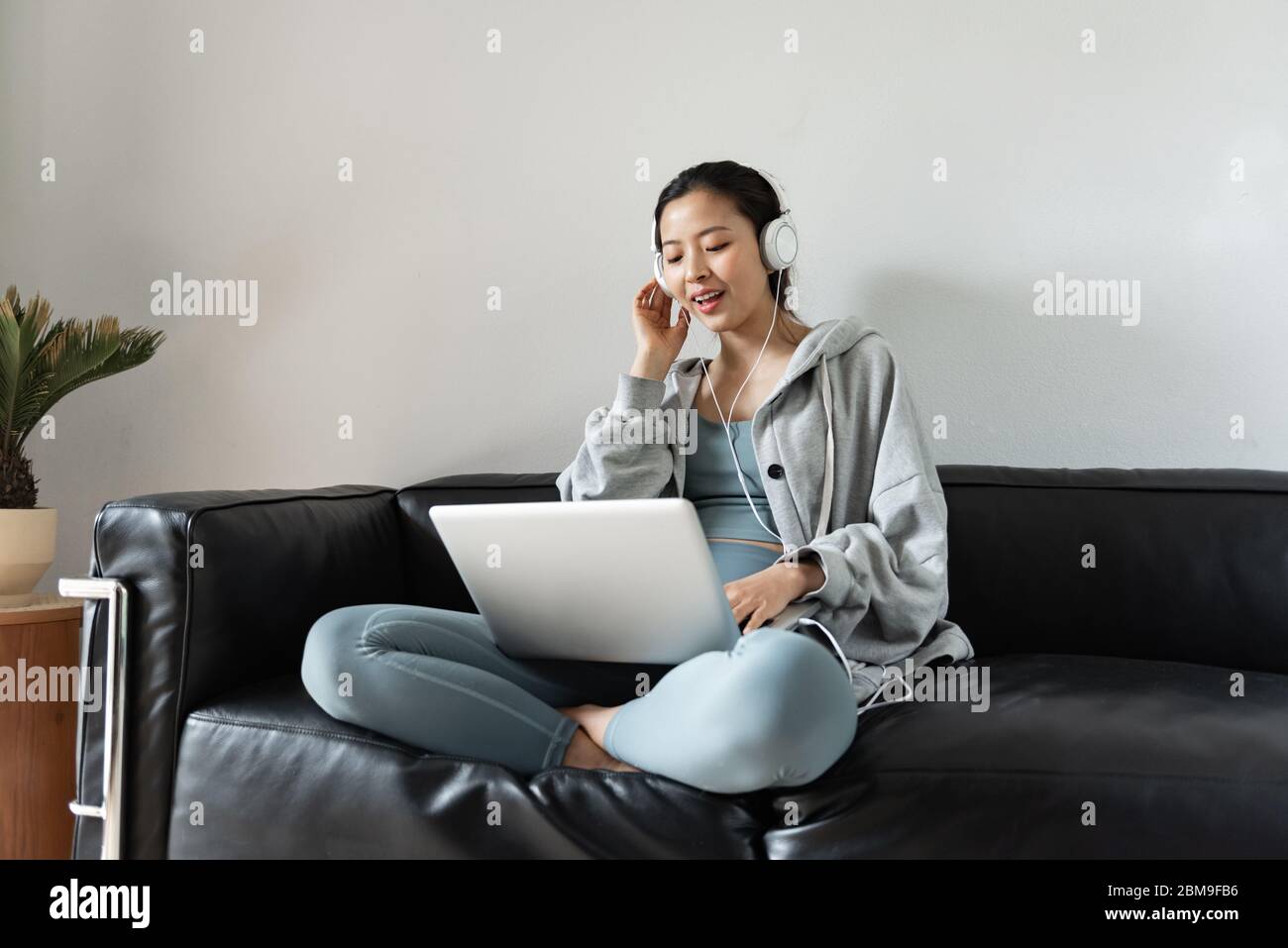 A young Asian woman using a computer in the living room Stock Photo - Alamy