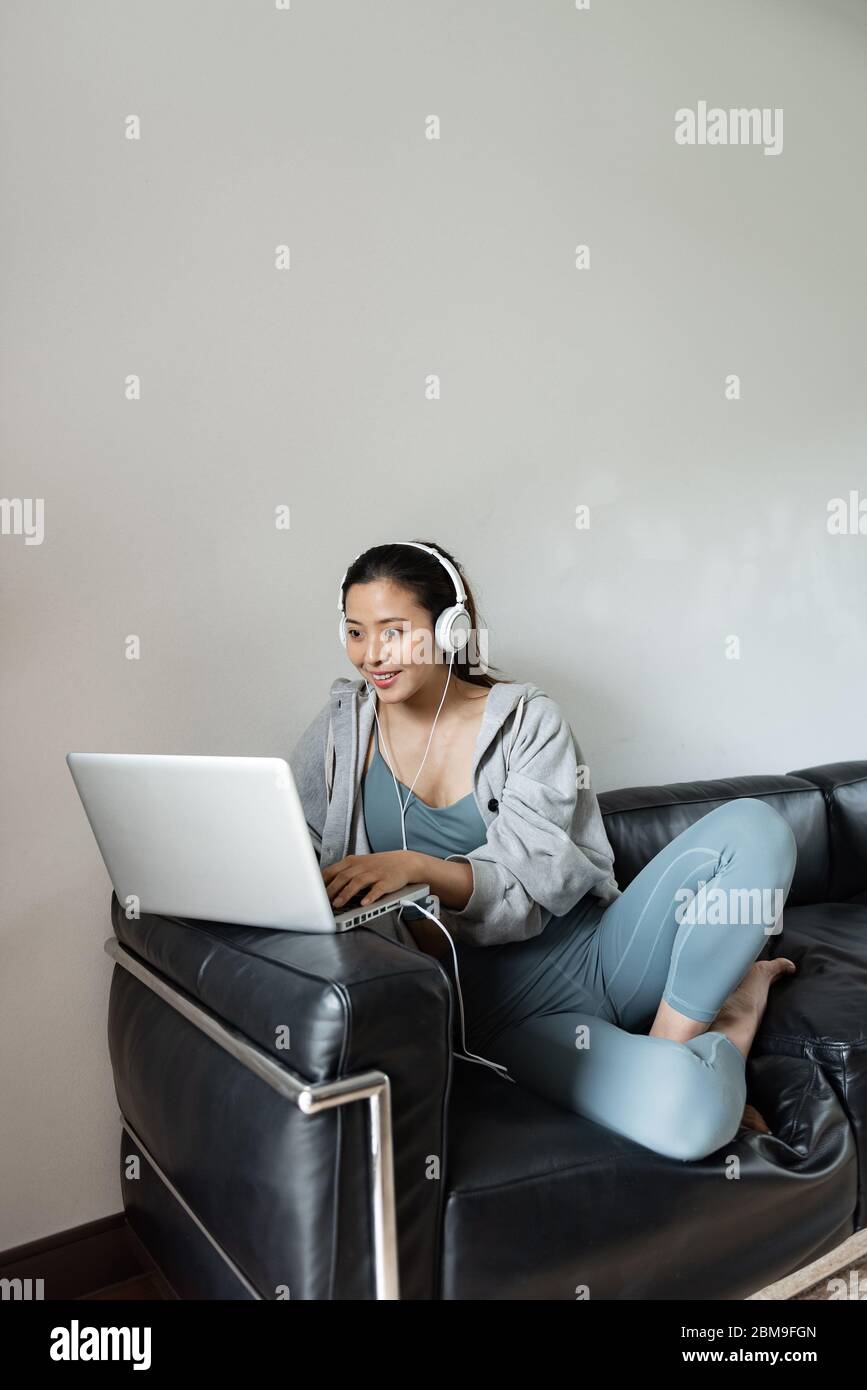 A young Asian woman using a computer in the living room Stock Photo - Alamy