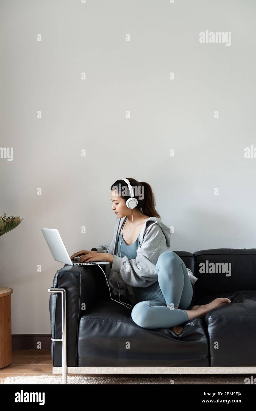 A young Asian woman using a computer in the living room Stock Photo - Alamy