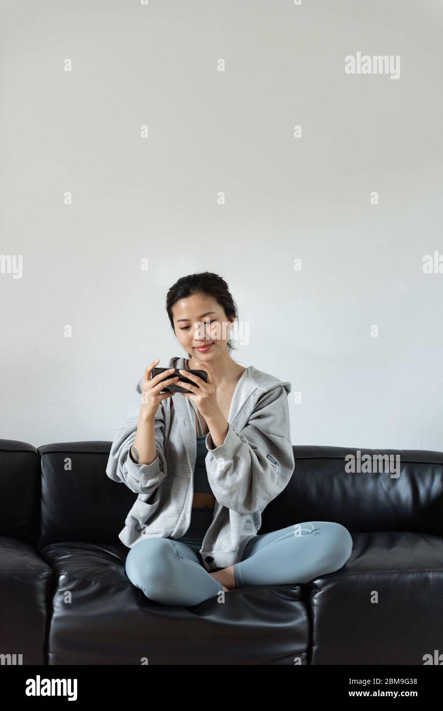 A young Asian woman using mobile phone in the living room Stock Photo ...