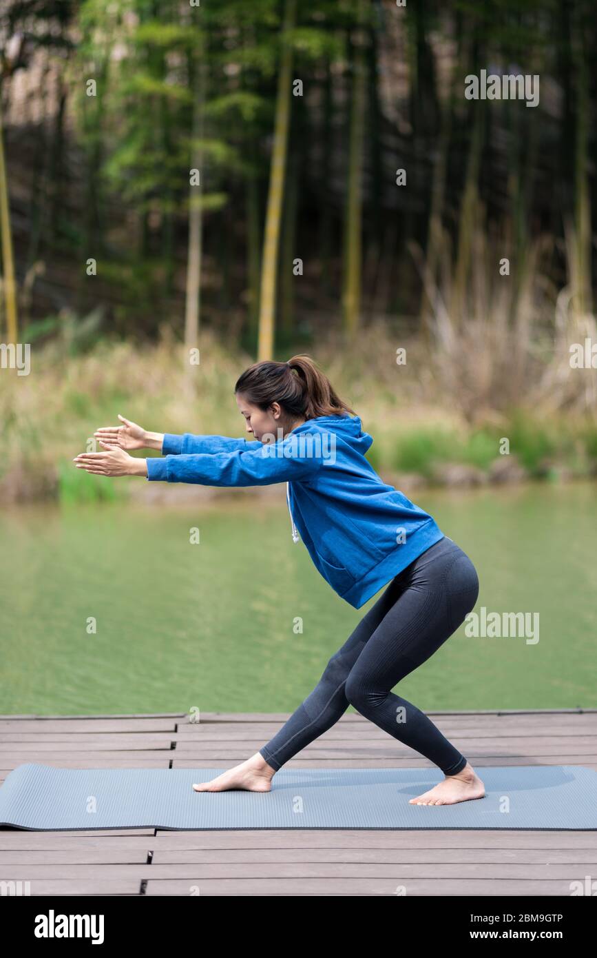 A young Asian woman doing yoga by the lake Stock Photo - Alamy