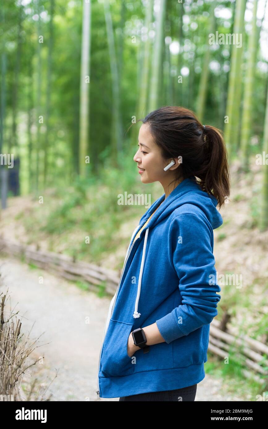 A young Asian woman walks and rests in a bamboo forest Stock Photo