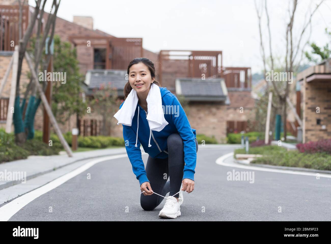 A young Asian woman squatting to tie shoelaces Stock Photo
