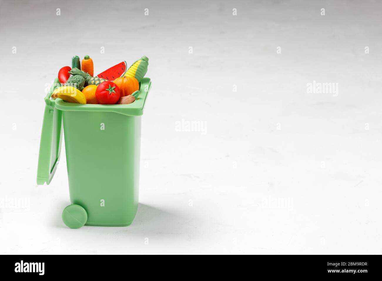 Food Waste Prevention Concept. Fruits and Vegetables falling into the Green Garbage Bin Stock