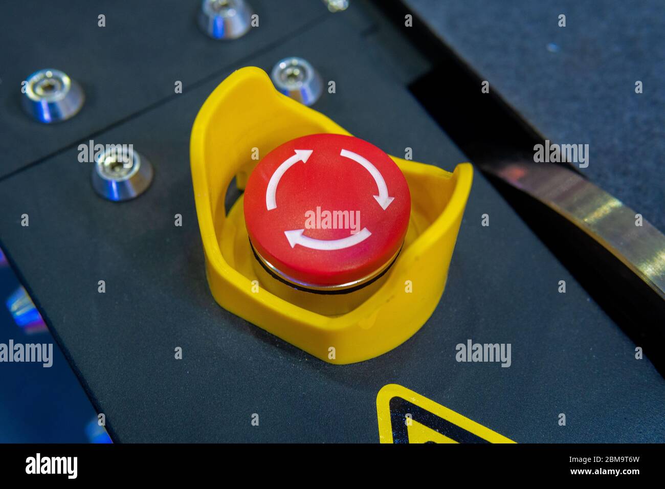 Red emergency button with arrows on black panel Stock Photo