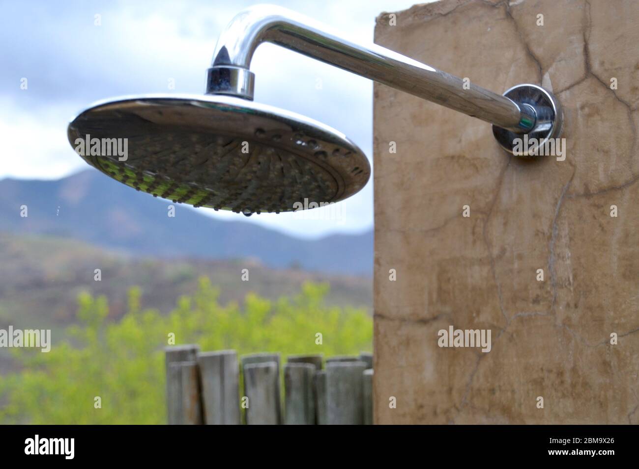Large silver rainfall showerhead in an outdoor shower in the South
