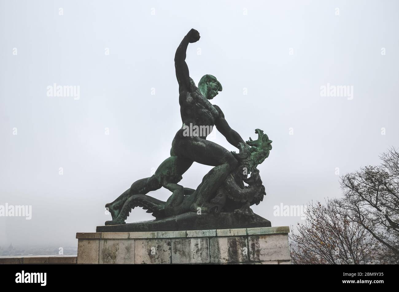 Budapest, Hungary - Nov 6, 2019: Side statue of the Liberty Statue on Gellert hill in Budapest in Hungary. Man slaying and strangling dragon, mythical expression of the fight between good and evil. Stock Photo
