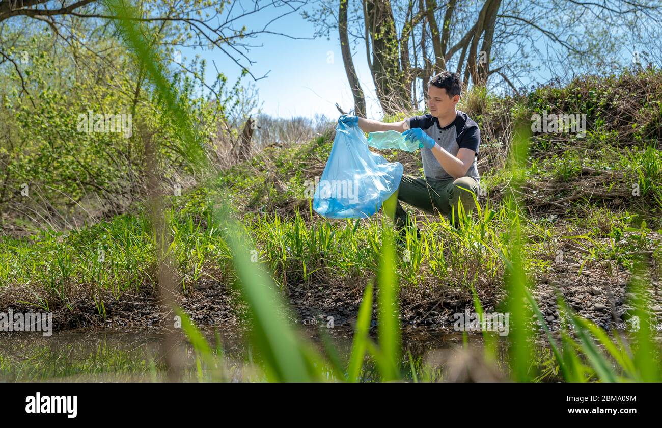 plastic bag with garbage hanging on tree in forest near the river.  pollution ecosystem problem , ecology environment trash Stock Photo - Alamy