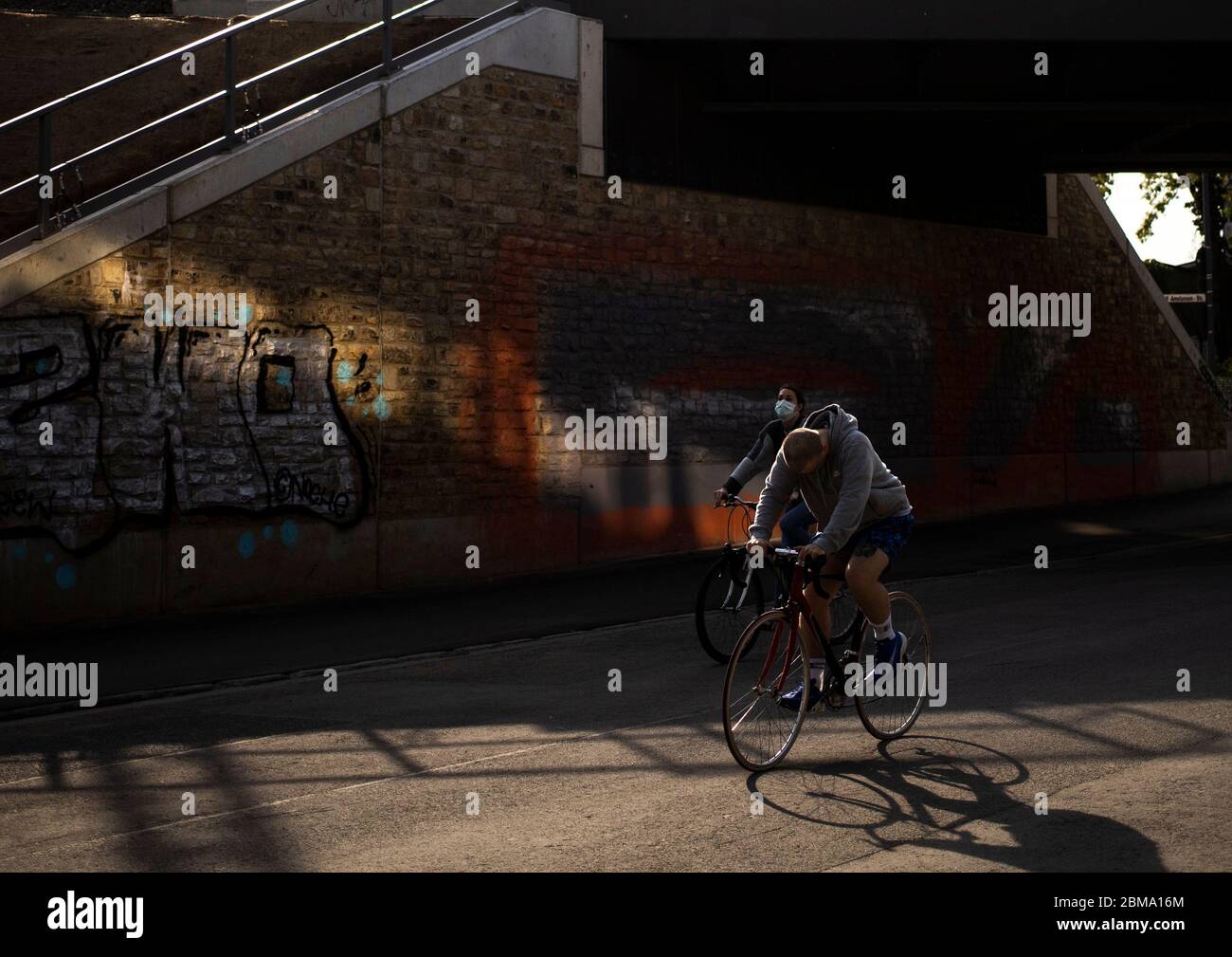 Kšln, Eifelwall, 07.05.2020: Lichtblick, Lichtreflexionen unter einer dunklen BrŸcke, eine Frau mit Mundschutz auf einem Fahrrad, Stock Photo