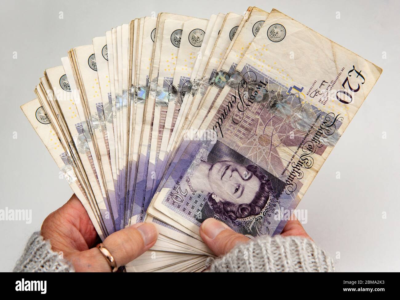 Womans hands holding a wad of twenty pound notes Stock Photo