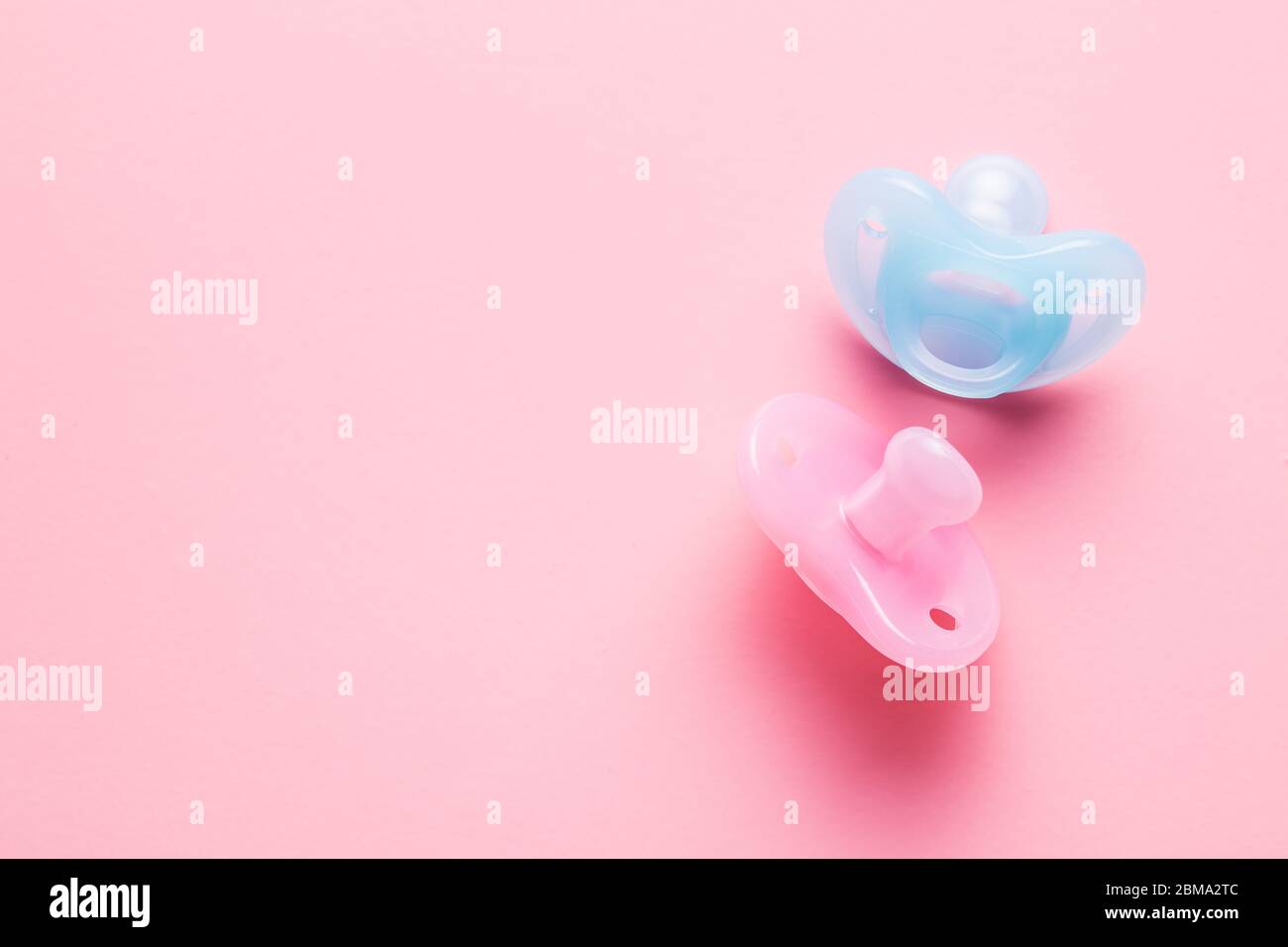 Silicone pacifier. Pink and blue baby pacifier on pink background. Stock Photo