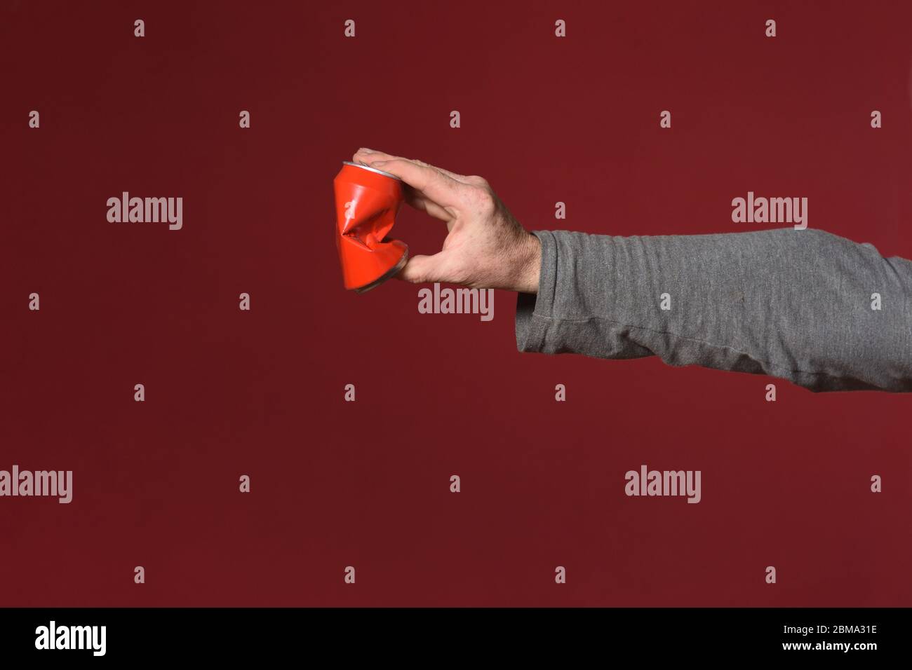 hand crushing a can of drink on red background Stock Photo Alamy