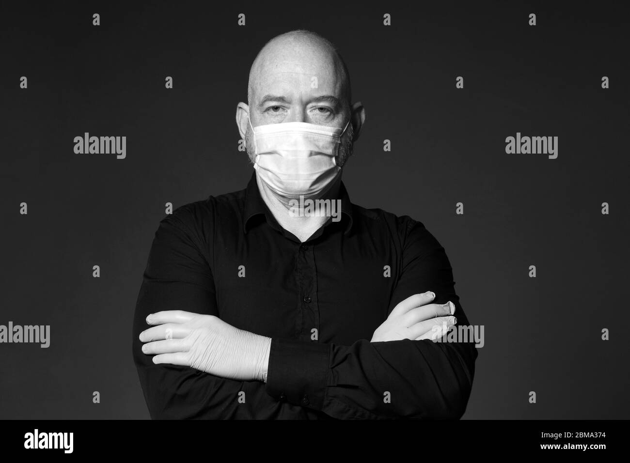 portrait of a man with gloves and mask arms crossed black and white