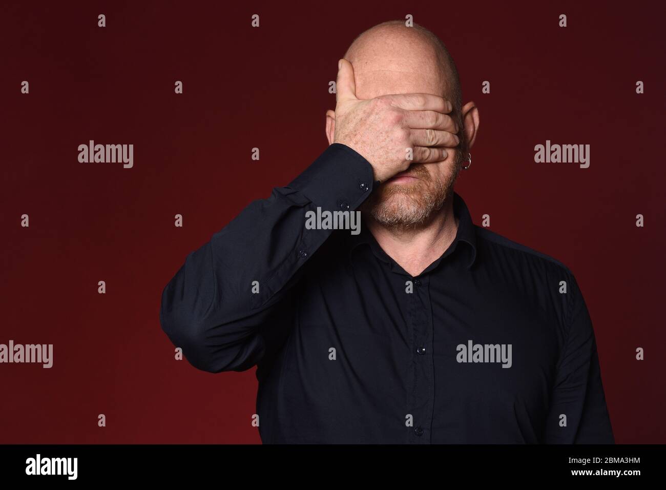 man cover his face on red background Stock Photo - Alamy