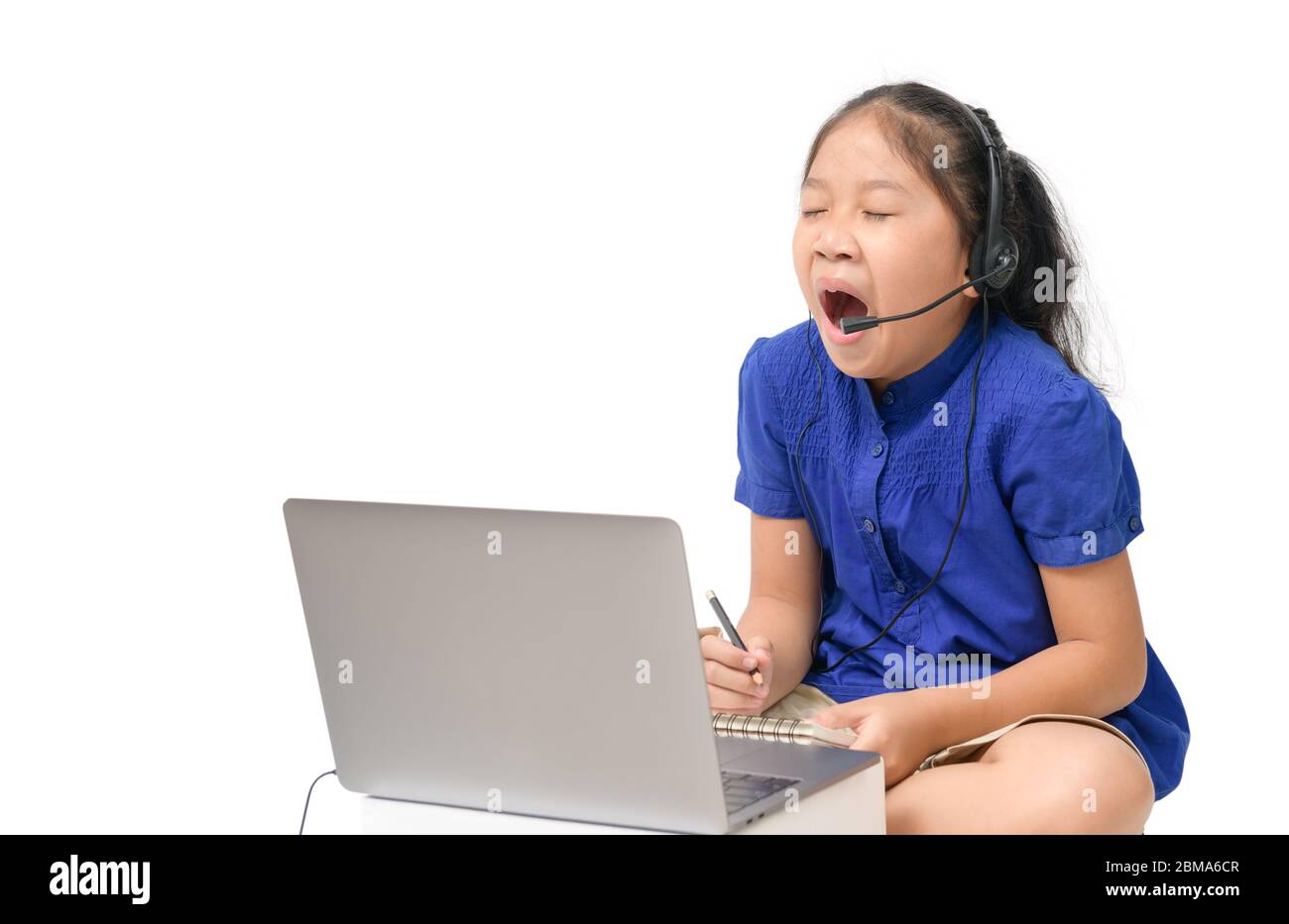 Coronavirus Outbreak. Lockdown and school closures. School girl watching online education classes yawning and bored at home. COVID-19 pandemic forces Stock Photo