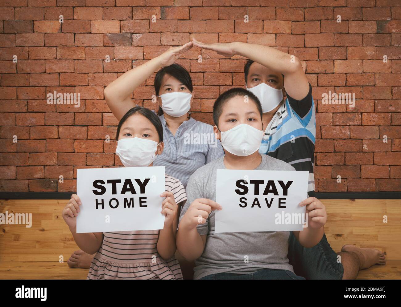 Asian  Family wear mask and shows paper with stay home stay save words at home, Coronavirus, COVID-19, self-quarantine, social disdancing concept. Stock Photo