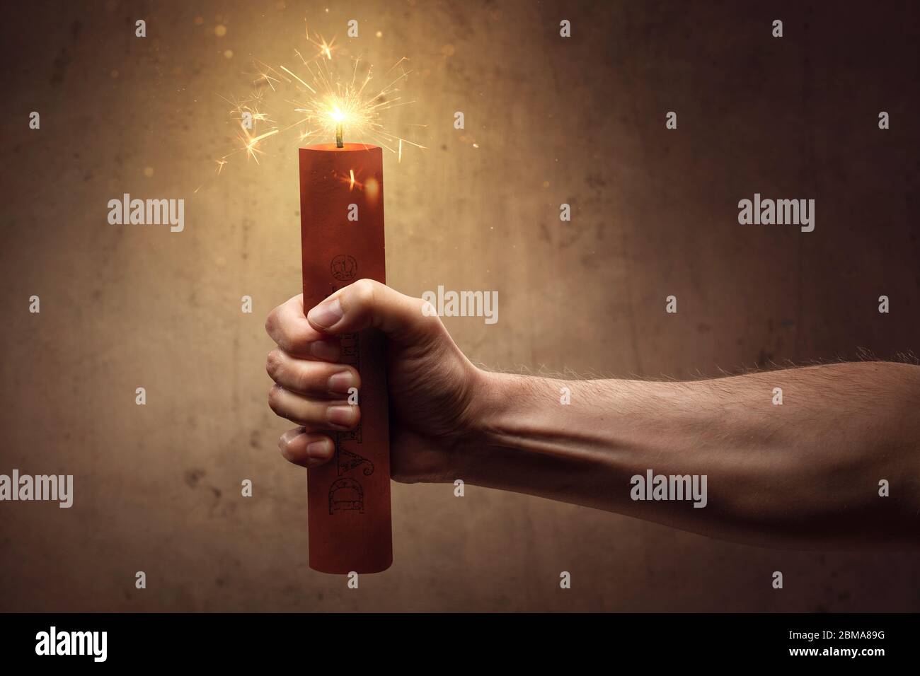 Risk concept - Hand holding a burning stick of dynamite Stock Photo