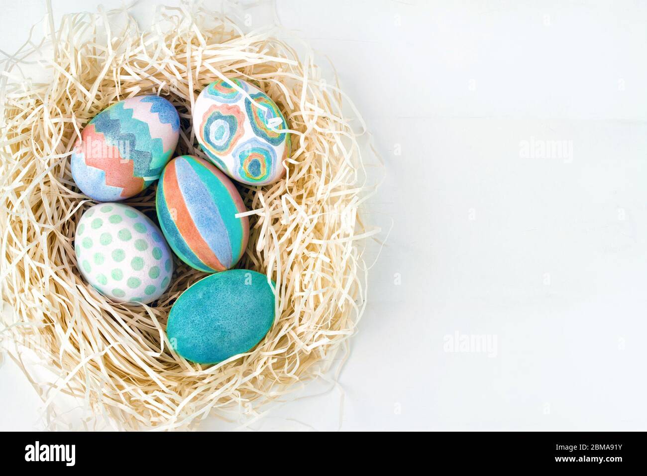 Flat lay of colorful Easter eggs in nest. Group of Easter eggs on white ...